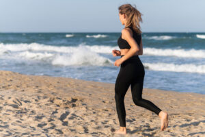 <mujer-corriendo-en-la-playa-haciendo-deporte>
