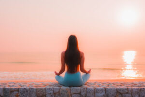 <mujer-meditando-al-atardecer-en-frente-del-oceano>