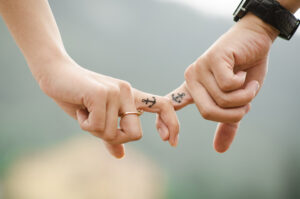 <pareja-dandose-la-mano-con-tatuajes-iguales>