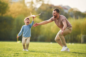 <padre-feliz-y-su-hijo-se-estan-divirtiendo-en-el-campo-en-verano>