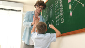 <feliz-chico-escribiendo-respuestas-en-la-pizarra-y-dando-cinco-altos-pedagogia>