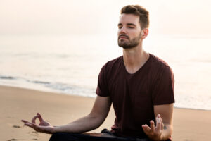 <hombre-practicando-yoga-en-la-playa>