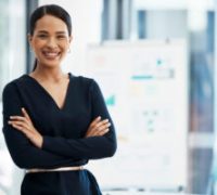 Confident, happy and smiling business woman standing with her arms crossed while in an office with a positive mindset and good leadership. Portrait of an entrepreneur feeling motivated and proud
