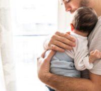 Affectionate love between father and newborn baby, father holding his son in arms in apartment