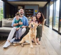 Portrait of smiling parents and their two cute young children sitting with their family golden retriever in their living room at home